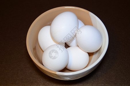位于黑暗背景的两色碗中的白鸡蛋 黑底面图片