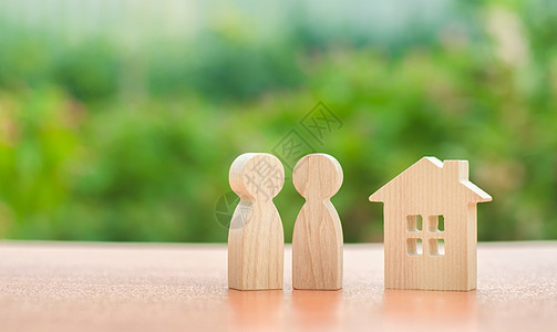两个木制人物和自然背景上的房子 经济适用房的概念 为年轻家庭和夫妇买房的抵押贷款 买卖房地产 家巢背景图片