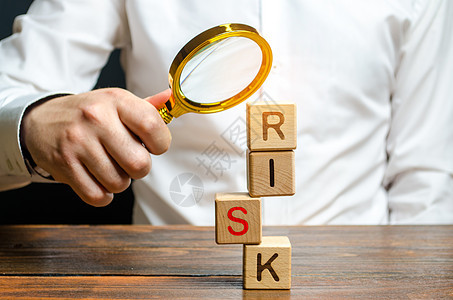 一个男人用 Risk 这个词探索立方体塔 错误和故障的搜索和更正 风险管理 成本评估以及业务和投资安全 增强业务弹性背景图片