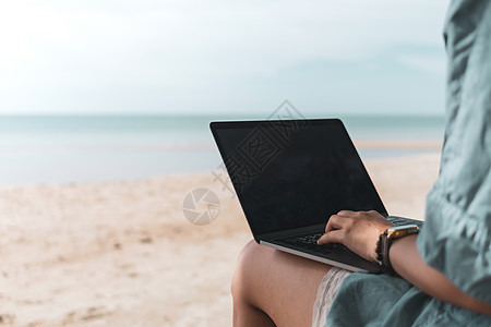 展示卡妇女使用笔记本电脑和智能手机在海滩背景的度假卡迪学习药片工作场所商业专注商务女士旅游假期社会背景