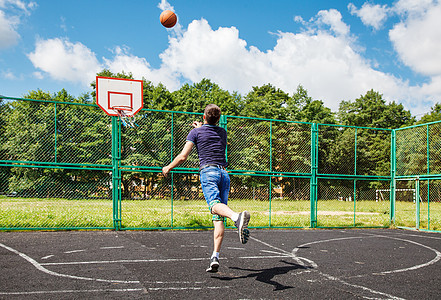 青年男子在运动场打篮球;图片
