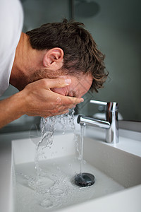 男人在水龙头流出的冷水下从水槽里的皮肤上洗脸冲洗肥皂 早上护肤程序 男性美容护肤洗面奶 面膜治疗图片