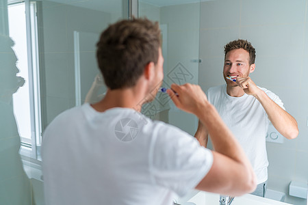 男人早上准备做卫生常规刷牙 看着家庭浴室的镜子 用牙刷清洁牙齿口腔护理图片