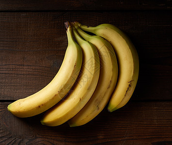 棕色木制桌子上一堆黄黄色无皮的成熟香蕉小吃食物热带饮食甜点皮肤木板水果图片