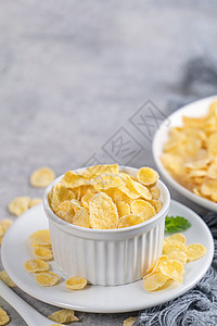 玉米薄片 奶粉和灰色水泥底面的蜜蜂碗糖 c小吃奶制品甜心饮食牛奶桌子玉米片勺子盘子早餐图片