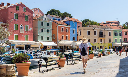 在克罗地亚亚得里亚州Adriatiat费用成本的古老传统收费城镇观光和享受暑假时看到身戴草用太阳帽的美丽金黄色年轻女旅行者旅游草图片