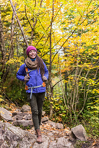 徒步旅行女孩背着背包走在山区的森林小径上 亚洲女性在秋季自然远足时 背着背包帽子和夹克 在户外探险旅行 享受好天气图片