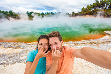 有趣的自拍情侣游客在新西兰泳池旅行 在怀奥塔普的五彩缤纷的地热温泉池中 年轻人闻到难闻的硫磺味而做出傻脸图片