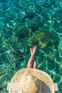 身戴大夏日太阳帽的女子在明亮的绿绿海边小木铁码头上放松海滩配件甲板太阳身体假期温泉水池游泳阴影图片