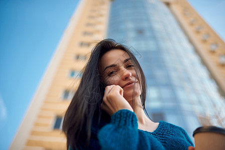 年轻 笑着的黑发美女 用她的智能手机在户外图片