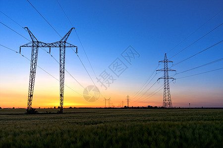 黄昏时的高高电线太阳农田黄色蓝色工业农村绝缘子天空发电厂技术图片