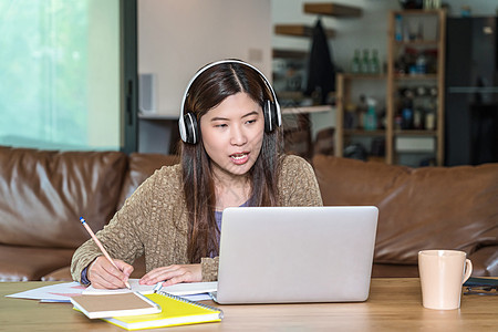 使用技术笔记本电脑和耳机的亚洲商业妇女学生网络女性学习讲话商务键盘咖啡杯女士职场图片