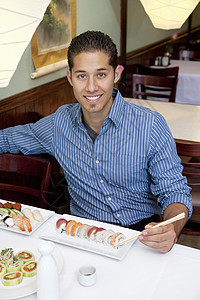 一个英俊的年轻人在日本餐厅吃寿司的肖像图片