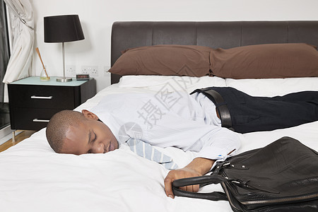 疲累的非洲裔美国青年商务人士睡床上睡觉图片