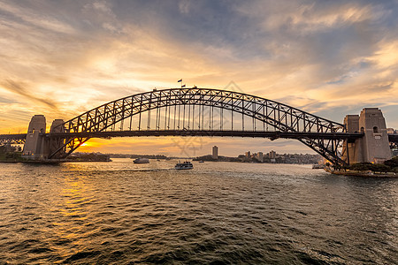 日落时悉尼海港桥和一艘帆船航行图片