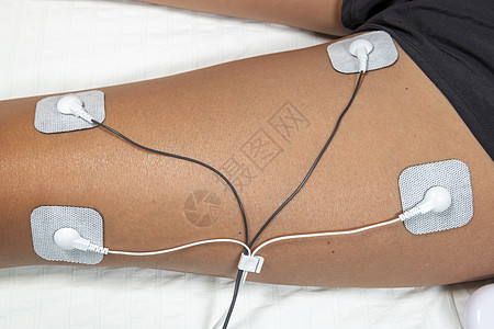 妇女在家里使用TENS和EMS机器 在其中一名男子的肌肉上皮肤技术刺激病人女性治疗电气神经电极震惊图片