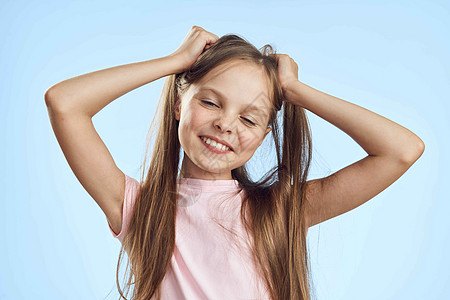 带着头发的女孩微笑着粉红色T恤衫蓝背景童年情感女性成功教育青少年乐趣蓝色眼睛展示孩子们喜悦图片