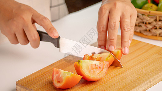 女人把新鲜番茄切成碎片 用刀砍木头图片
