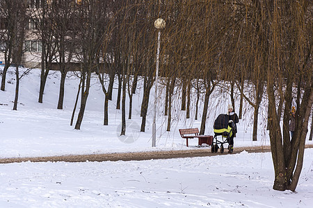 冬天 一个年轻女子在公园里带着一块石板走来走去图片