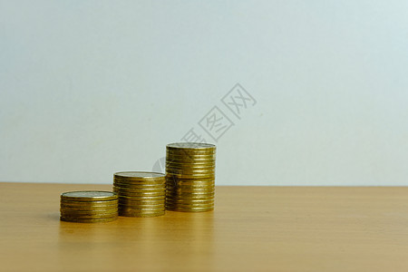 白背景的木桌上堆满金钱硬币图片