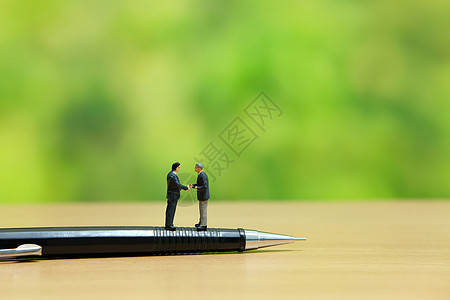 商业战略概念照片  两个微型商务人士站在笔上签订握手合伙协议咨询领导者风暴工作创新领导数字解决方案经理玩具图片