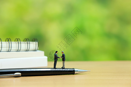 商业战略概念照片  两个微型商务人士站在笔上签订握手合伙协议投资风暴解决方案商务数字硬币领导者思考咨询经理图片