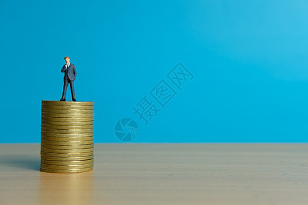 微型商业概念     商务人士站在金硬币堆架之上债务贷款生活男人金融生长人士玩具支付危机图片