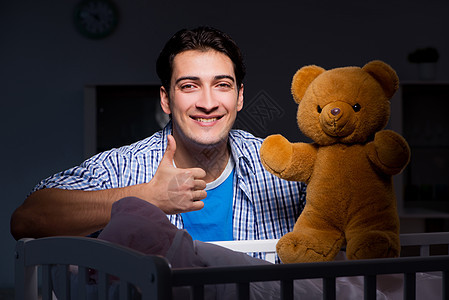 快乐的爸爸在夜间照顾新生儿婴儿睡眠幸福动物女儿婴儿床男人苗圃拇指母性房间图片
