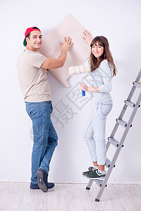 年轻家庭在家里用新墙纸翻新家房改造示范房子建设者夫妻丈夫胶合装潢工人妻子图片