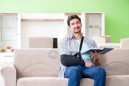 坐在沙发上 手受伤的青年学生男子教科书手臂扭伤疼痛骨科手术病人治疗药品考试图片
