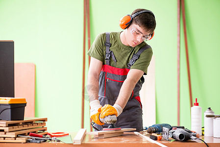 在工作间工作的青年木工工人噪音地板修理工木匠木头房子硬木安全抛光抛光机图片