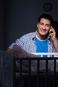 快乐的爸爸在夜间照顾新生儿婴儿父母微笑女儿童年孩子感情手机男人家庭电话图片
