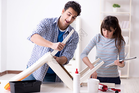 妻子帮助丈夫修理家里破碎的椅子扳手夫妻女士安装木匠维修修理工内阁男人工作图片
