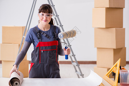 妇女为壁纸工作做准备装潢建设者微笑工作服胶水改造建造滚筒修理工维修图片