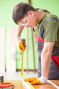 在工作间工作的青年木工工人建筑修理地板仪表工匠测量手工房子木头工作台图片