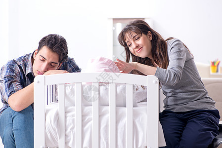 年青父母在床铺旁有新生儿的幼年父母家庭母性卧室童年睡眠父亲摇篮护理幸福女孩图片