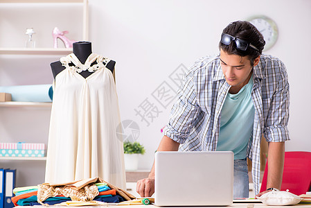 年轻英俊裁缝在其车间工作工作室电脑厘米服装材料商业纺织品工艺手工业设计师图片
