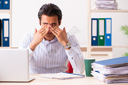坐在办公室的年轻雇员电脑笔记本文书货架职场员工商务压力公司学生图片