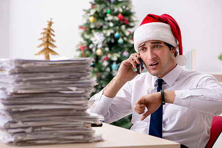 圣诞轮班在办公室工作的年轻工人手表桌子超载会计商业审核庆典人士员工假期图片