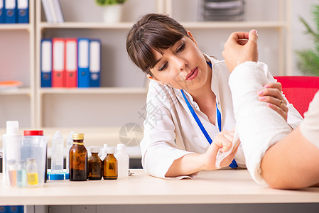 带绷带手臂的青年男子看女医生外伤治疗师创伤药品手术保健援助事故保险扭伤包扎图片