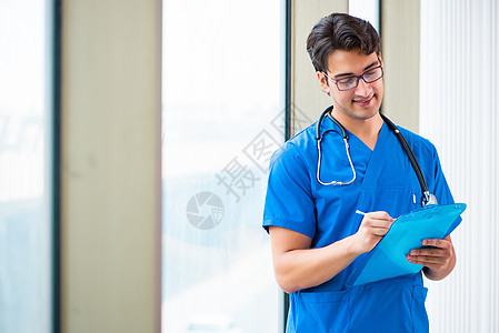 在医院工作的英俊的年轻医生窗户学生办公室临床咨询实习生考试药品治疗师写作图片