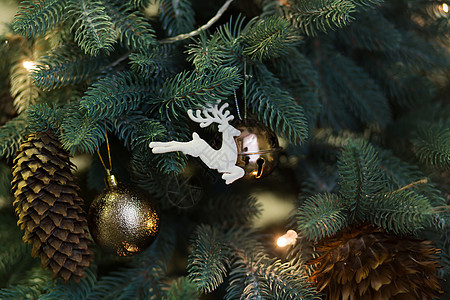 圣诞树树枝和锥形之间 有装饰性的玩具白鹿松树卡片金子庆典风格假期装饰品花环传统火花图片