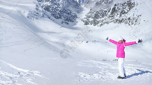 身穿粉红色滑雪夹克 手套 帽子和滑雪靴的快乐少女图片