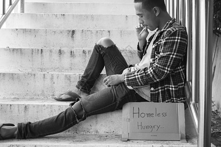 坐在天桥上的无助的流浪汉乞丐寂寞失业人行道男性难民杯子社会成人城市图片