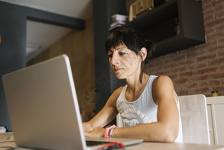 在家使用笔记本电脑的妇女办公衬衫专注金发互联网工作自由职业者窗户咖啡桌子图片