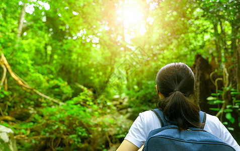 带着背包在绿林中旅行的快乐的亚洲女人图片