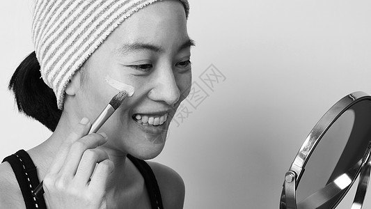 美丽的亚洲女性美容脸 用液态打成的肤色白色治疗液体魅力化妆品粉末艺术家刷子褐色图片