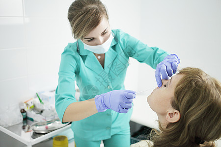 一名身戴医疗面具的护士从病人鼻子上抽取鼻梁消毒剂防护保健流行女孩专家感染家庭医生社工预防图片