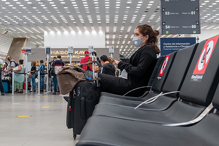 机场候机室真正的妇女 尊重健康的距离测量标准 戴面部面具的女性女士行李手提箱柜台假期座位飞机手机航空公司图片