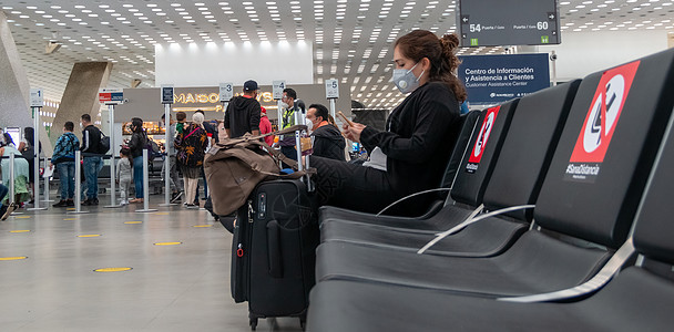 机场候机室真正的妇女 尊重健康的距离测量标准 戴面部面具的手机预防度假者飞机座位旅行女士航空公司手提箱运输图片